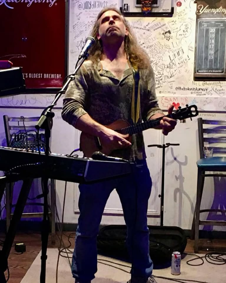 Russ performing with a ukulele at a lively brewery