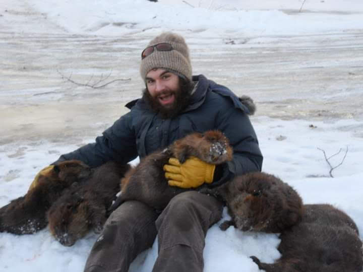 Russ sitting in the Alaska snow with several beavers