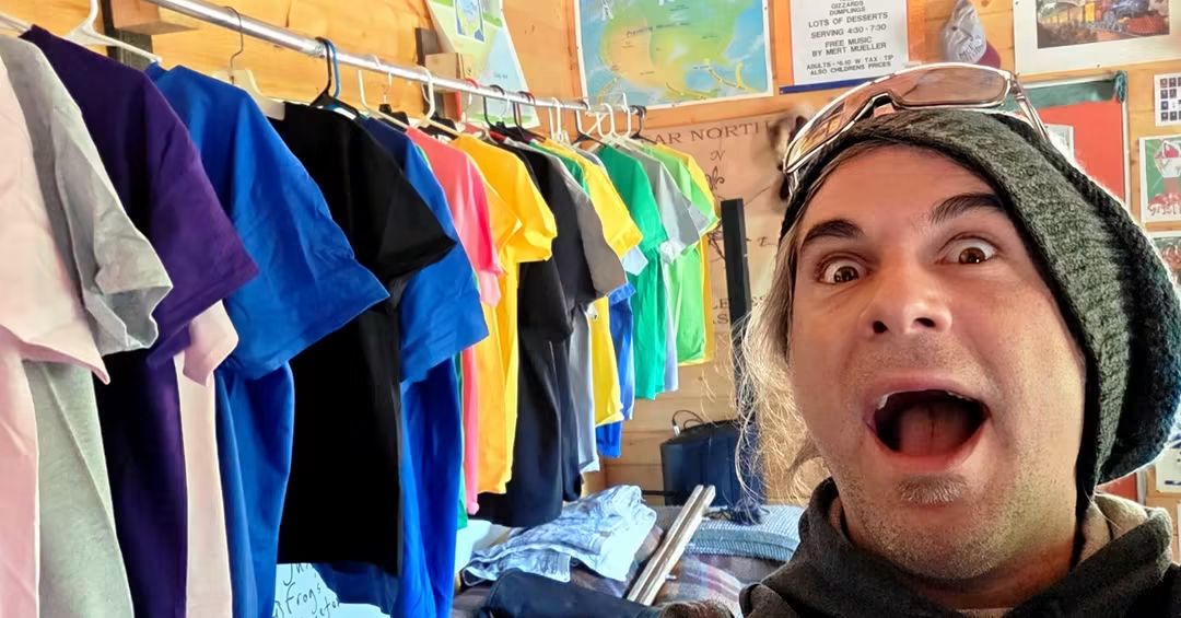 Ukulele Russ with a rack of handmade shirts in several colors