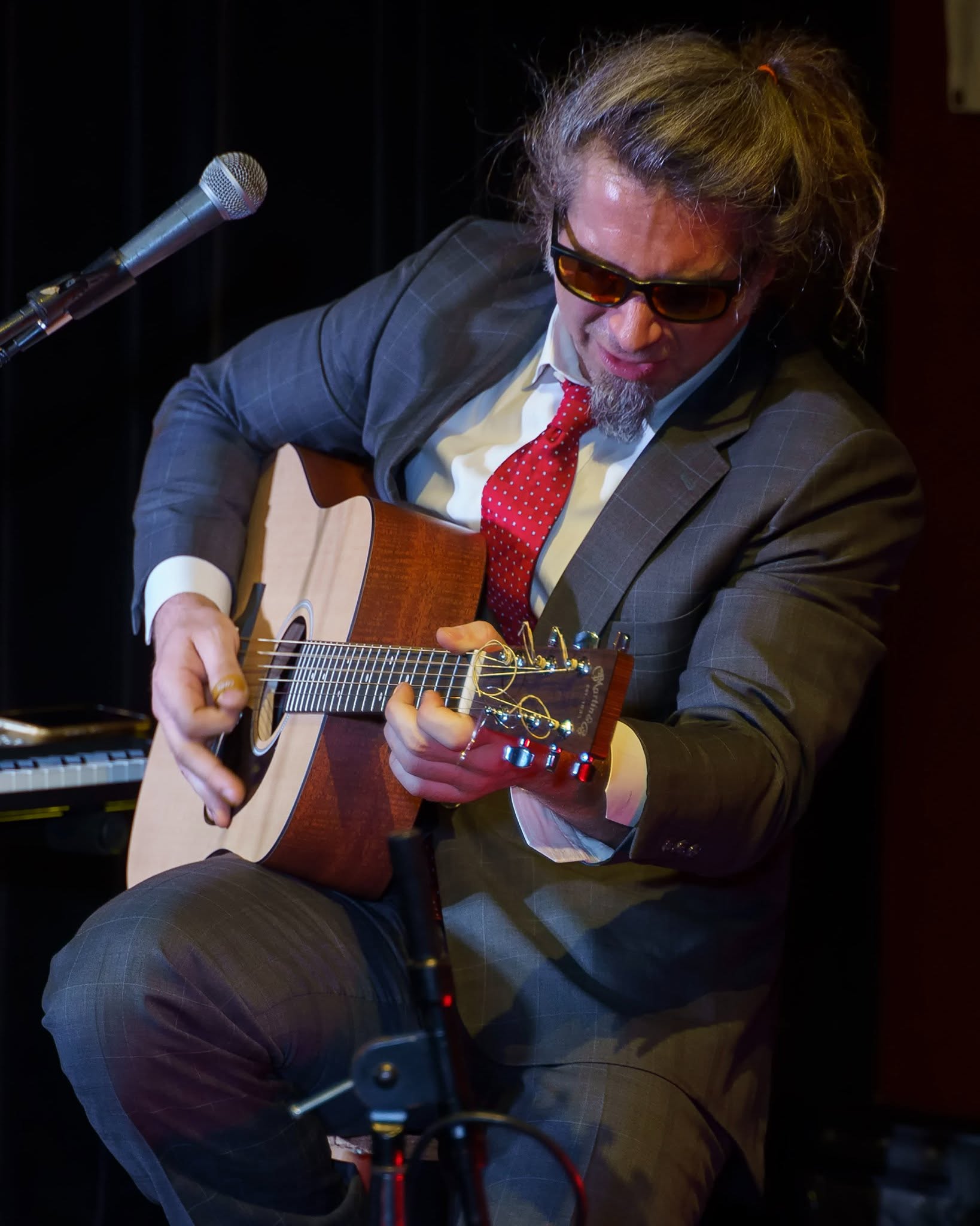 Russ performing in a suit with an acoustic instrument